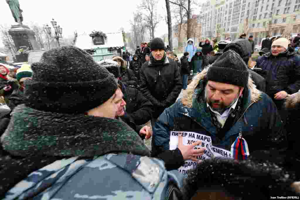 Один из примеров провокации: неизвестный человек пытается буквально силой вручить плакат оппозиционного содержания активисту